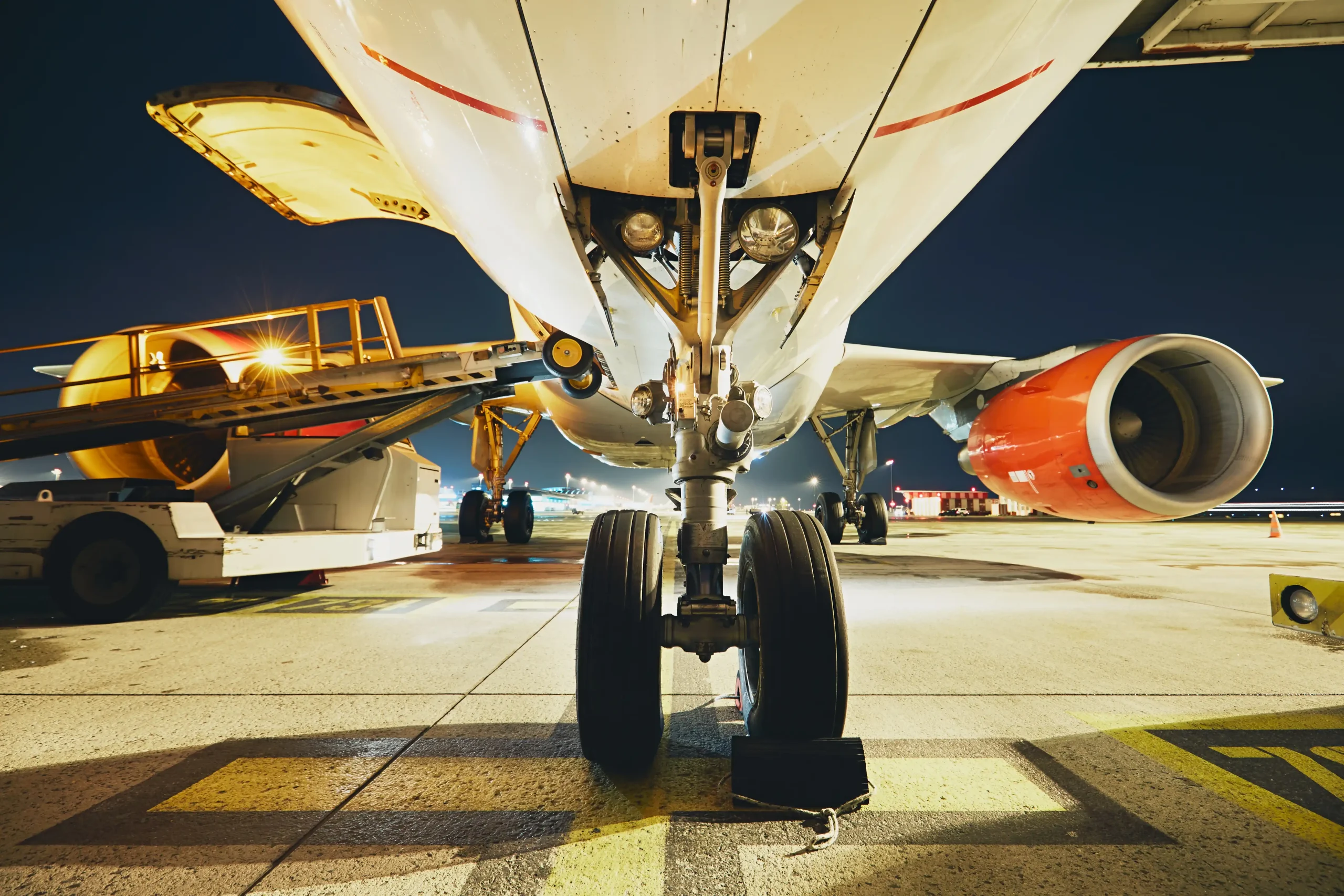 Close-up view of a commercial aircraft on the airport ramp at night.