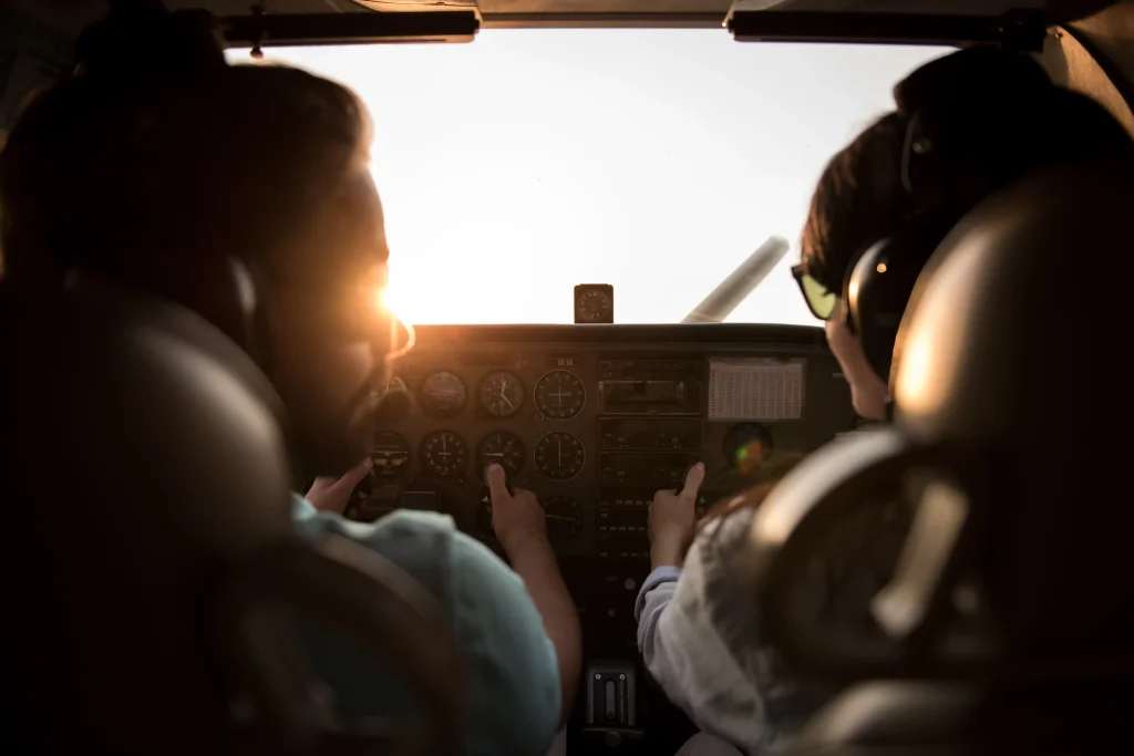 Pilots flying an aircraft from the cockpit during sunset